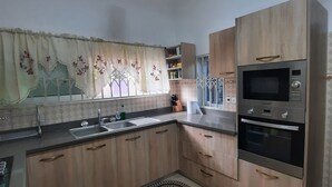 Cocina con armarios de madera, un lavamanos de acero inoxidable, un microondas y un horno.