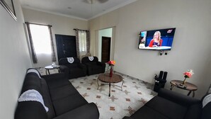Una sala de estar con sofás negros, una mesa de centro y un televisor en la pared.