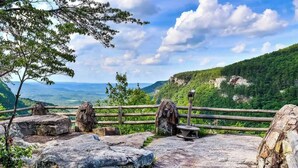 A scenic viewpoint with a wooden railing, large rocks, and a telescope. - Waterfall Cottage | Hot Tub, Game Room, Fireplace (Mentone)