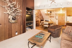 Un salon avec un mur en bois, une table basse en verre, un fauteuil marron et un canapé.