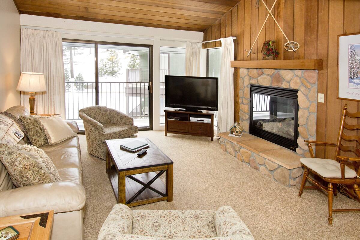 A cozy living room with a stone fireplace, a television, and comfortable seating.