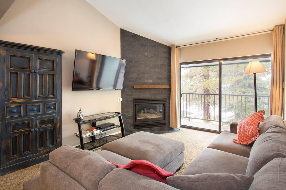 A living room with a fireplace, a television mounted on the wall, and a sofa.