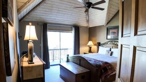 Ein Schlafzimmer mit Bett, Nachttischen, Deckenventilator und Blick ins Freie.