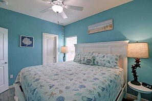 Un dormitorio con cama, ventilador de techo, ventana y lámpara.