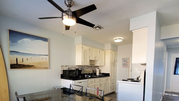 A modern kitchen with white cabinets, a black countertop, and a built-in stove. - Great house on close to two acres with fishing pond (Oklahoma City)