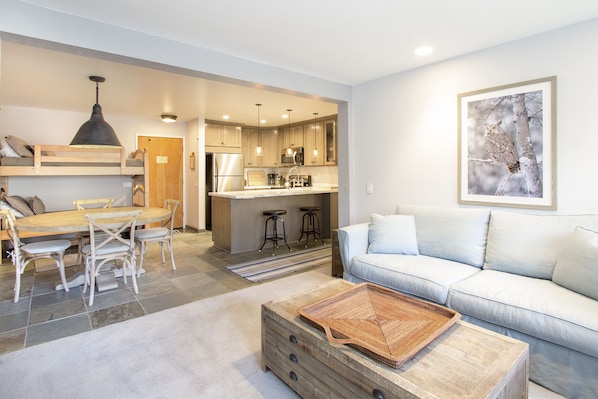 A modern living space with a dining area, kitchen, and a sofa.
