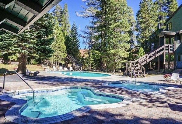 A pool area with two hot tubs, surrounded by trees and a wooden deck. - St. Anton Condos with Rec Center (Mammoth Lakes)