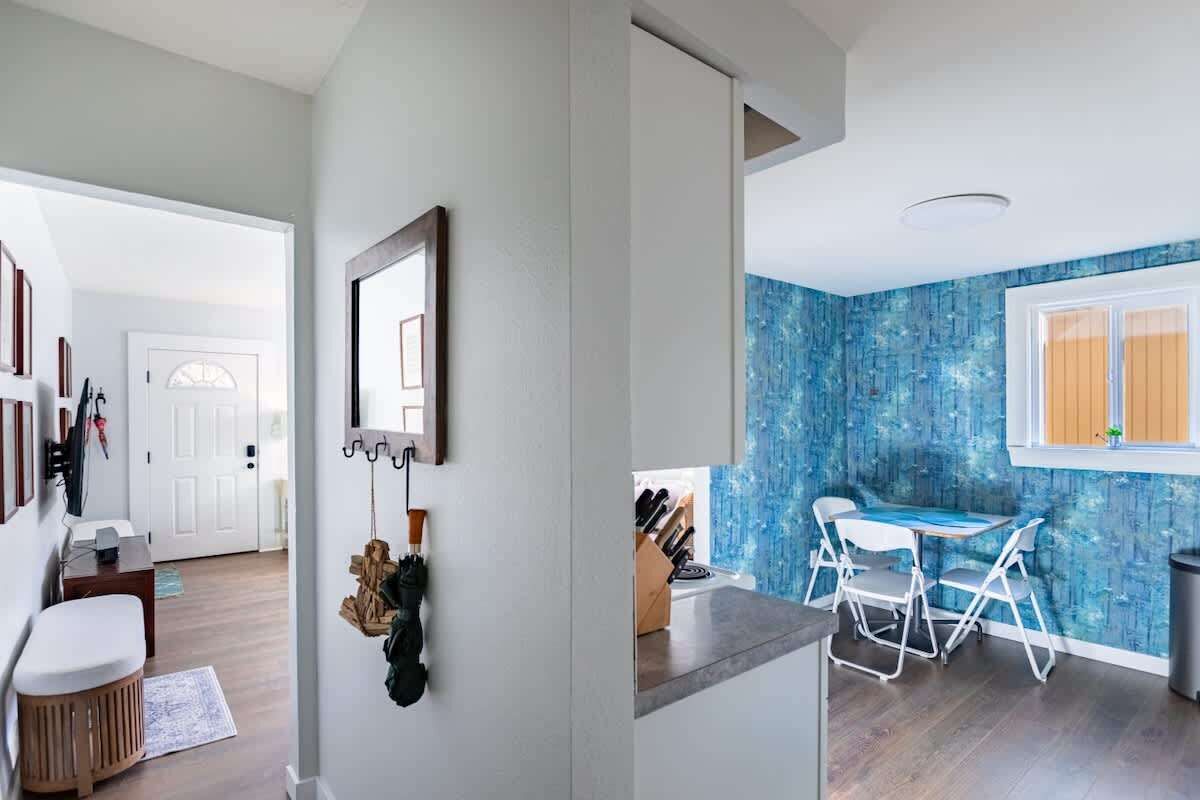 A modern kitchen with a blue backsplash, white cabinets, and a dining area with a table and chairs.