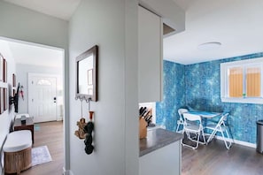 A modern kitchen with a blue backsplash, white cabinets, and a dining area with a table and chairs.
