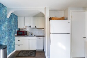 A compact kitchen with white cabinets, a red microwave, and a white refrigerator.