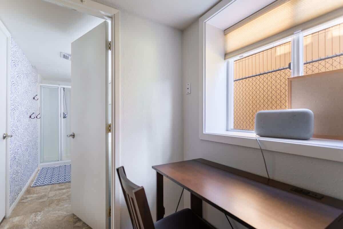 Une pièce comprenant un bureau, une chaise et une fenêtre donnant sur une clôture.