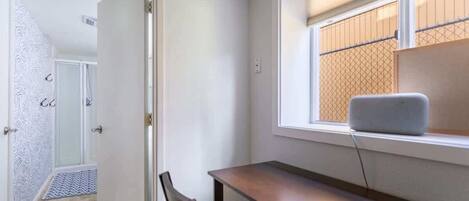 Une pièce comprenant un bureau, une chaise et une fenêtre donnant sur une clôture.