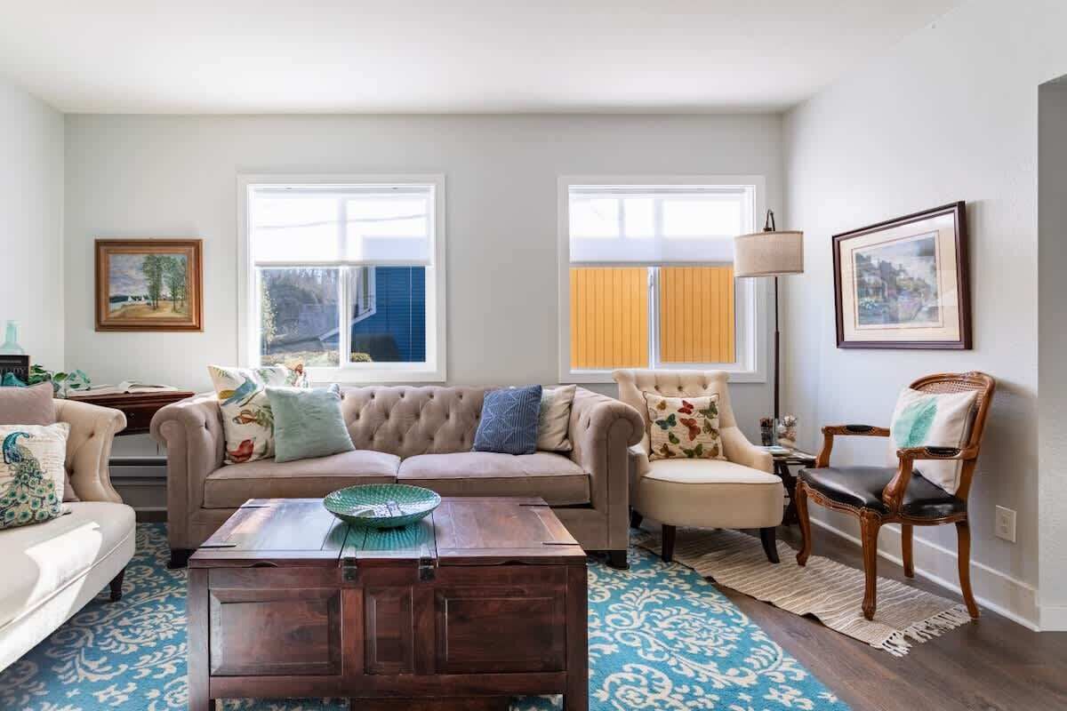 A living room with a beige sofa, a wooden coffee table, and a patterned rug.