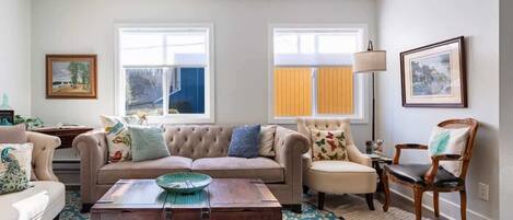A living room with a beige sofa, a wooden coffee table, and a patterned rug.