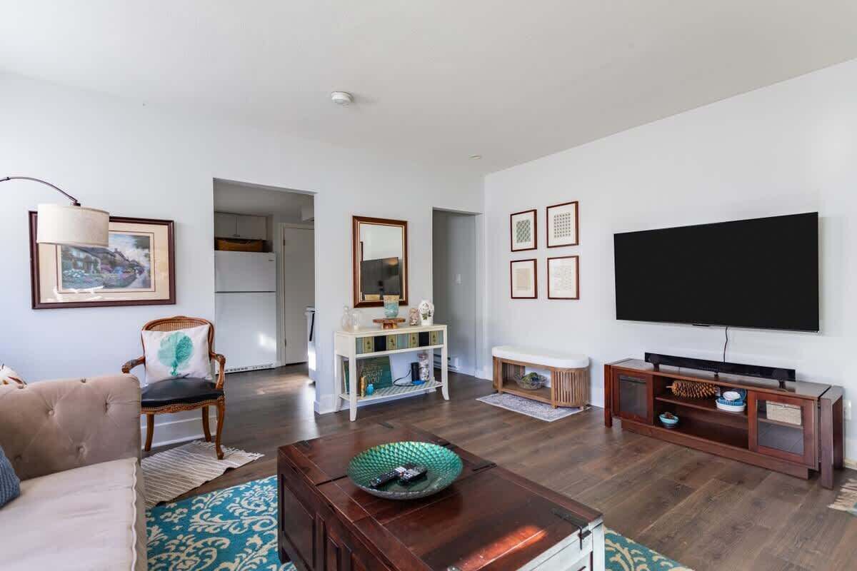 A living room with a sofa, a chair, a coffee table, a TV, and a console table.