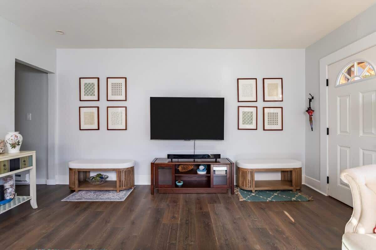 A living room with a flat-screen TV, two side tables, a wooden entertainment unit, and framed pictures on the wall.
