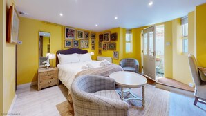 A bedroom with a bed, bedside tables, a chair, a round table, and a balcony with a chair.