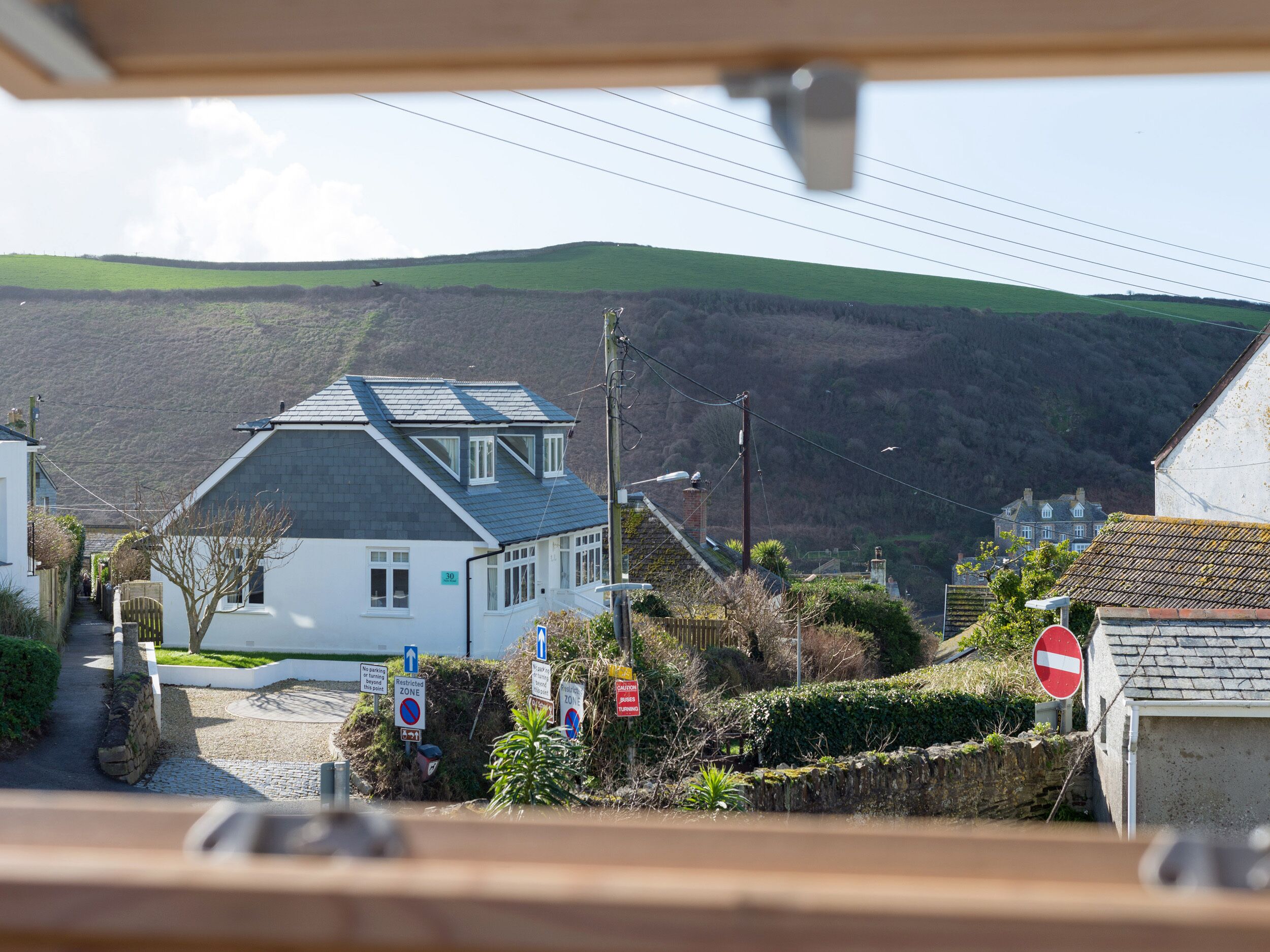A residential area with houses, a no entry sign, and a hill in the background.