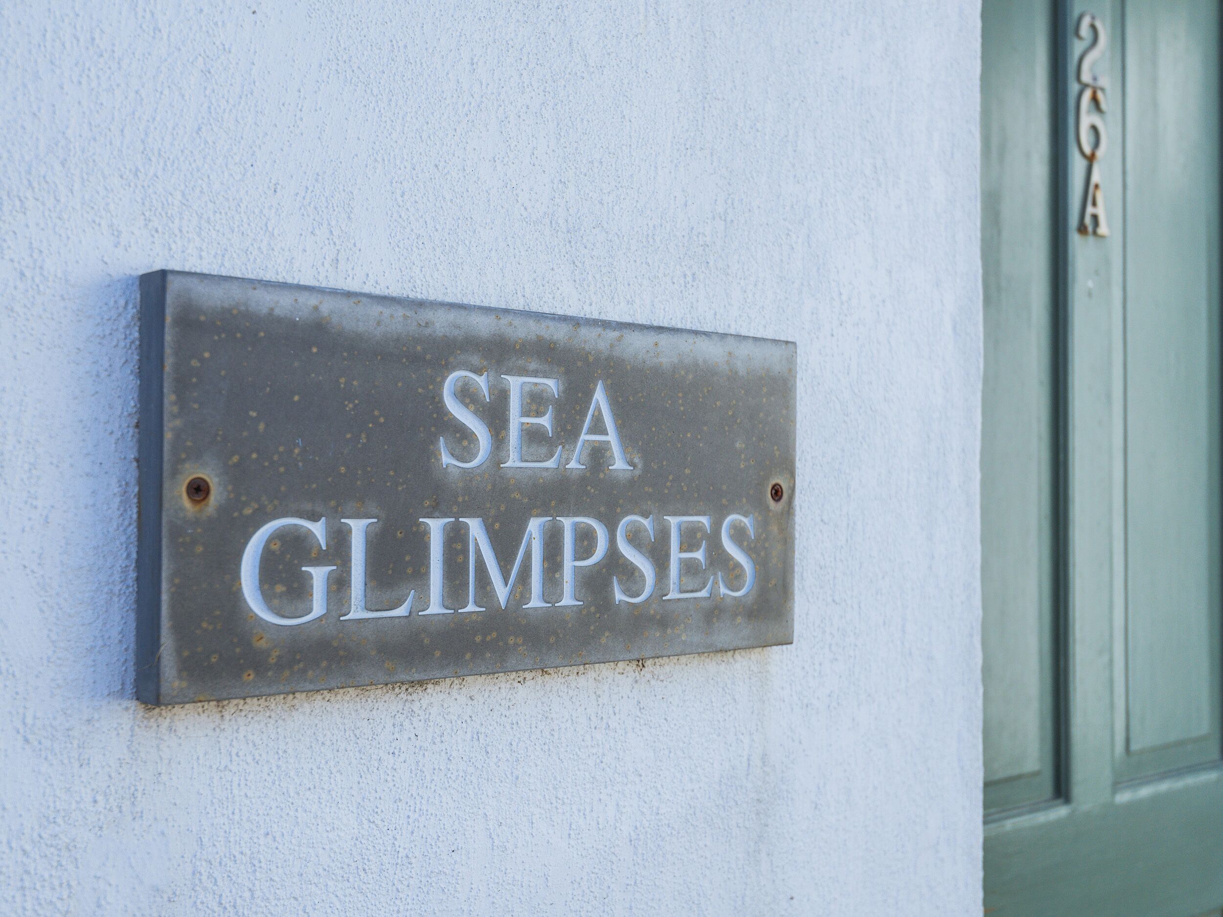 Ein Metallschild mit der Aufschrift 'SEA GLIMPSES', an einer Wand befestigt.