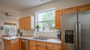 A modern kitchen with wooden cabinets, stainless steel appliances, a built-in dishwasher, and a window with a view of trees. - Boho 2b/2ba Downtown/OldTown, Patio w/fire feature (Albuquerque)