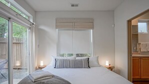 A bedroom with a large bed, two bedside lamps, a window with blinds, and a view of the outdoors. - Boho 2b/2ba Downtown/OldTown, Patio w/fire feature (Albuquerque)