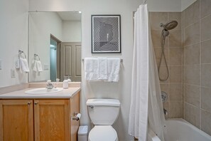 Ein Badezimmer mit Waschbecken, Spiegel, Toilette, Dusche und einem gerahmten Bild an der Wand.
