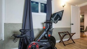 A Peloton exercise bike in a room with a window, a door, and a small wooden chair. - Fresh Walkable Fremont Home Near Ballard/Downtown (Seattle)