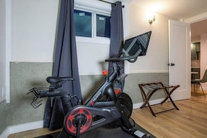 A Peloton exercise bike in a room with a window, a door, and a small wooden chair. - Fresh Walkable Fremont Home Near Ballard/Downtown (Seattle)