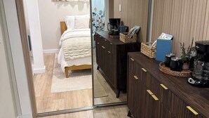 A hotel room with a mirrored wardrobe, a bed with a white duvet, a coffee machine, and a small table with a basket and magazines. - Fresh Walkable Fremont Home Near Ballard/Downtown (Seattle)