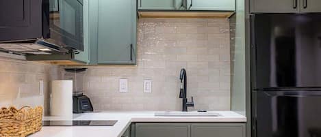 Una cocina con un refrigerador de acero inoxidable, un microondas y un lavamanos.