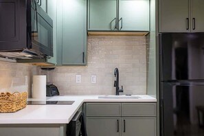 Eine Küche mit einem Edelstahl-Kühlschrank, einer Mikrowelle und einem Spülbecken.