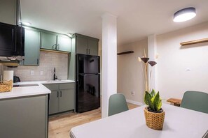 Une cuisine compacte équipée d’un réfrigérateur, d’un évier et d’un coin repas avec une table et des chaises.