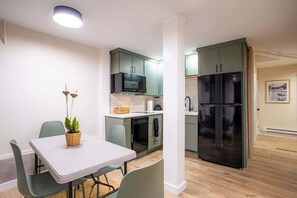 Cocina compacta con microondas, lavavajillas y refrigerador negro.
