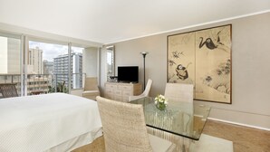 A modern hotel room with a large bed, a glass dining table, a flat-screen TV, and artwork on the walls. - Lovely Studio in the Heart of Waikiki – A/C, Wi-Fi, FREE Parking! Sleeps 2 (Honolulu)