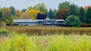 Un bâtiment moderne doté d’un toit plat et de grandes fenêtres, entouré d’un champ et d’arbres.