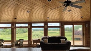 L’intérieur de ce chalet accueillant est doté d’un grand lit, d’un canapé et d’une table à manger. De nombreuses fenêtres offrent une vue sur l’extérieur.