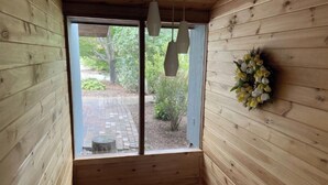 Un intérieur en bois donnant sur un chemin pavé et sur la verdure environnante.