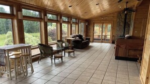 Une pièce spacieuse avec de grandes fenêtres, un coin repas avec une table et des chaises, un canapé et une cheminée.