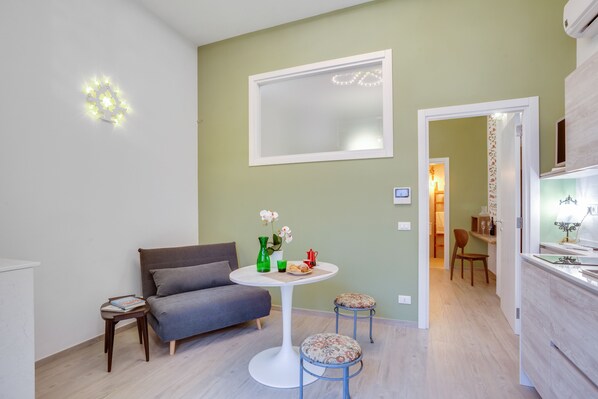 A modern living room with a sofa, a round table with a vase of flowers, and a small stool. - MADAME BARI' Apt a step from the sea (Bari)