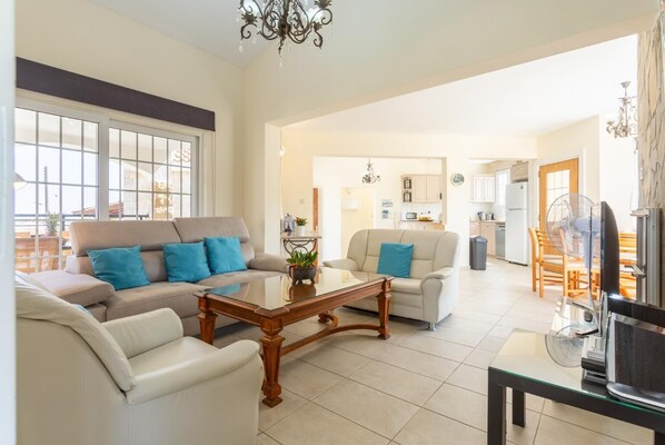 A spacious living room with a sofa set, a coffee table, and a dining area with chairs.
