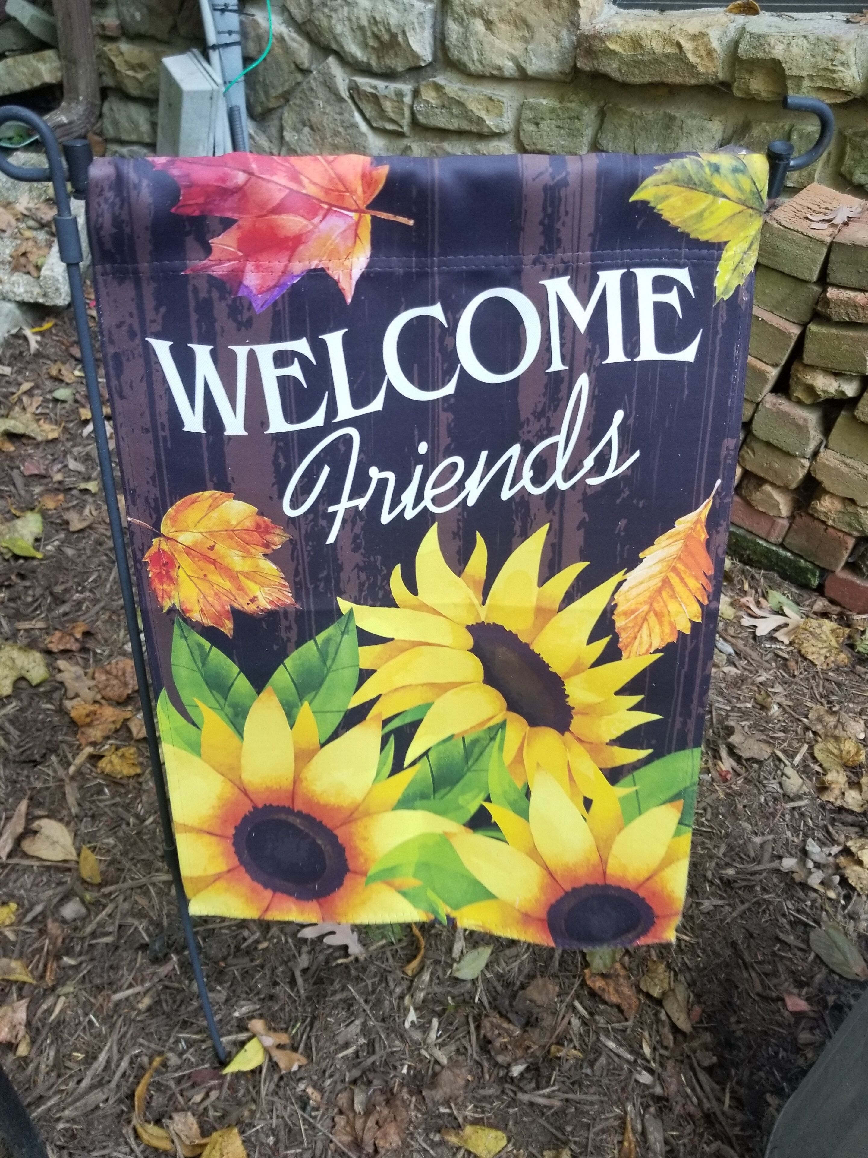 A welcome sign with autumn leaves and sunflowers.