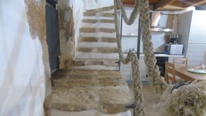Eine rustikale Steintreppe mit Seilgeländer, die zu einem Küchenbereich mit einfachen Annehmlichkeiten führt.