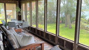 A wooden deck with a sofa, chairs, and a hanging plant. - Cabin on the Mississippi River (Trempealeau)