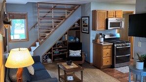 A living room with a sofa, coffee table, lamp, and a staircase leading to another level. - Cabin on the Mississippi River (Trempealeau)