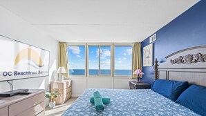 Una camera da letto con un letto, una scrivania, una lampada, una pianta in vaso e vista sul mare.