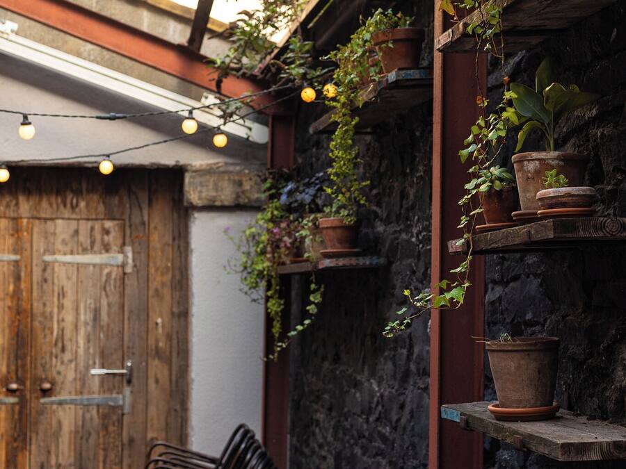 A patio area with a table and chairs, potted plants, and string lights.