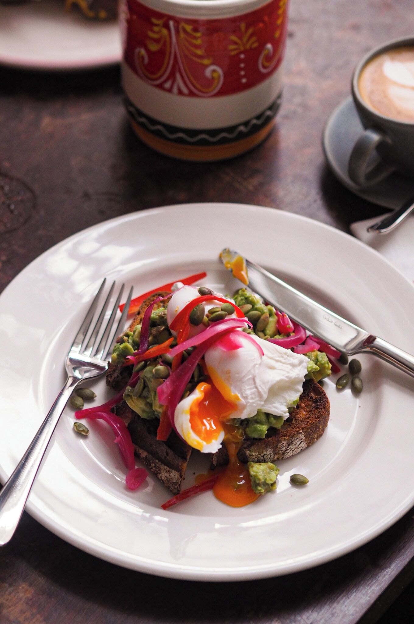 A plate with a breakfast dish, a fork, a knife, and a cup of coffee on a table.