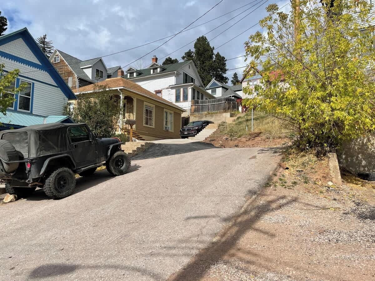 En bostadsgata med hus, en grusuppfart och ett parkerat terrängfordon.