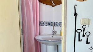 A bathroom with a pink shower curtain, a sink, and a mirror. There is a wall-mounted light switch and a power outlet. - Dream room (Hergla)