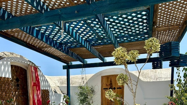A covered outdoor area with tiled flooring, potted plants, and a wooden bench. - Dream room (Hergla)
